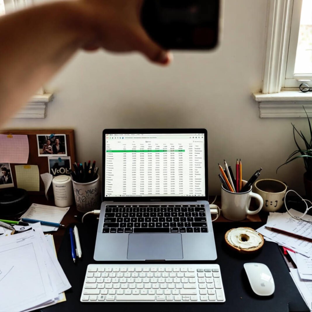 Cluttered desk with laptop showing VOO ETF screener and half-eaten bagel.